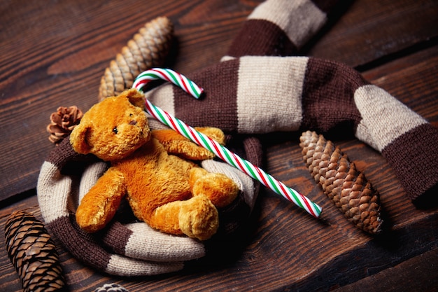 Teddybär und Zuckerstange mit Schal auf Holztisch