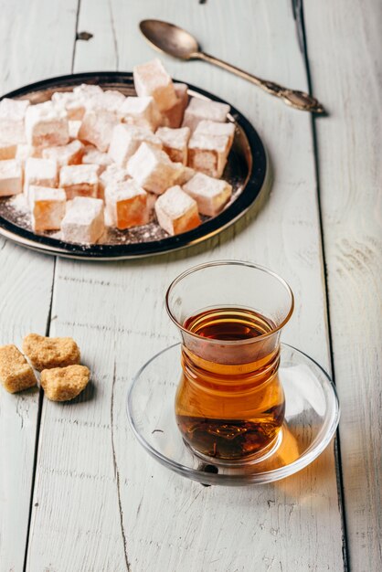 Tee im arabischen Glas mit türkischem Genuss Rahat Lokum über Holzoberfläche