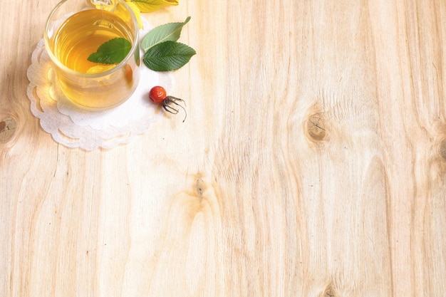 Tee im Glas auf einem Holztisch mit Blättern und Beeren