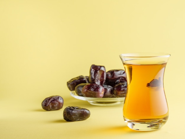 Tee in einem traditionellen türkischen Becher mit Datteln. Traditionelles Iftar-Essen im Ramadan.