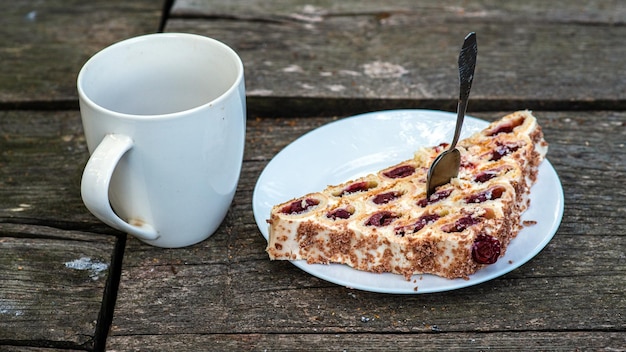 Tee in einem weißen Becher auf einem Holztisch neben einem Apfelkuchen auf einem weißen Teller