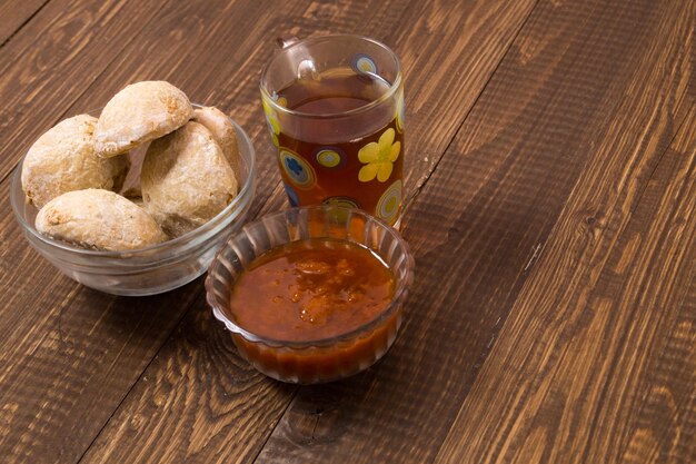 Tee in einer Tasse, Brötchen und Marmelade stehen auf dem Tisch