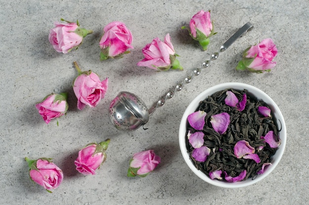 Tee mit Blütenblättern und Rosenknospen auf einem grauen strukturierten Tisch. Ansicht von oben. ÃƒÂƒÃ‚ÂƒÃƒÂ‚Ã‚Â ÃƒÂƒÃ‚Â‚ÃƒÂ‚Ã‚Â¡lose-up. Flach liegen.