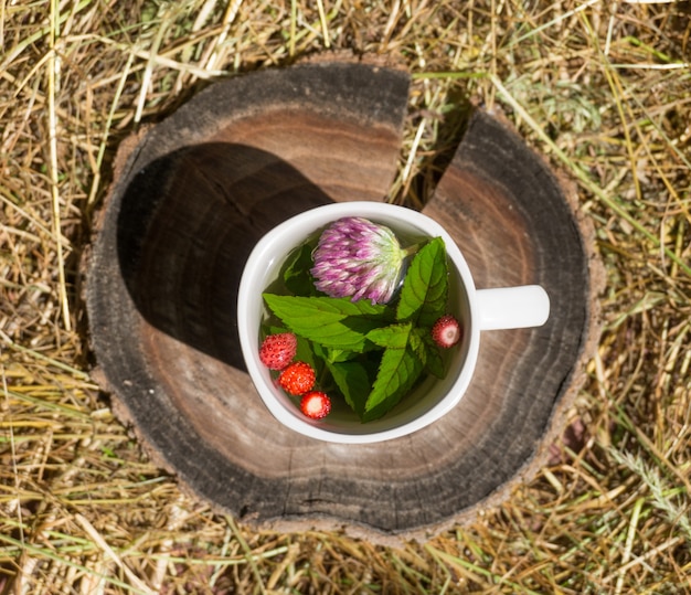 Tee mit Minze und Erdbeeren in einer weißen Tasse