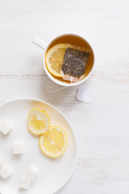 Tee mit Zitrone auf weißem Holztisch