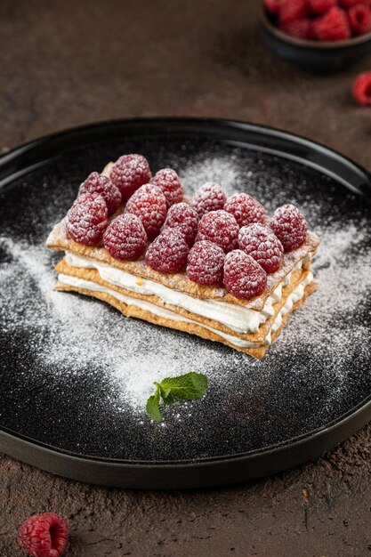 Tee und Süßigkeiten auf dunklem Hintergrund Mille Feuille von Erdbeeren Himbeeren in Schwarzblech