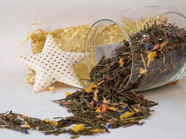 Tee wird aus einer Papiertüte in Form einer Welle auf Weiß gestreut Trockenkräuter mit gelben Blütenblättern zum Brauen Teeshop-Konzept