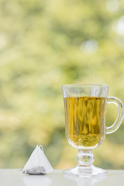 Teebeutel und Tasse Tee auf grünem Sommerhintergrund