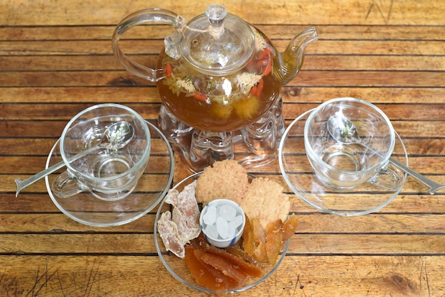 Teekanne aus Glas mit Tassen und Holztisch aus kristallisierten Früchten