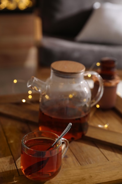 Teekanne und Tasse mit heißem Tee auf dem Tisch drinnen