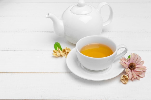 Teekanne und Tassen Tee auf einem weißen hölzernen Hintergrund
