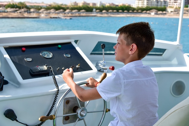 Teen am Steuer steuert eine Yacht auf See.