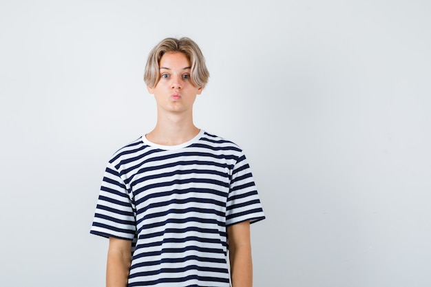 Foto teen boy schmollende lippen im t-shirt und schauen positiv, vorderansicht.