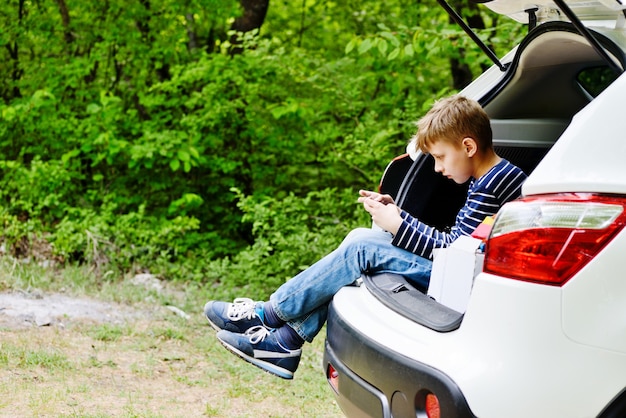 Teen Boy sitzt im Auto mit Telefon