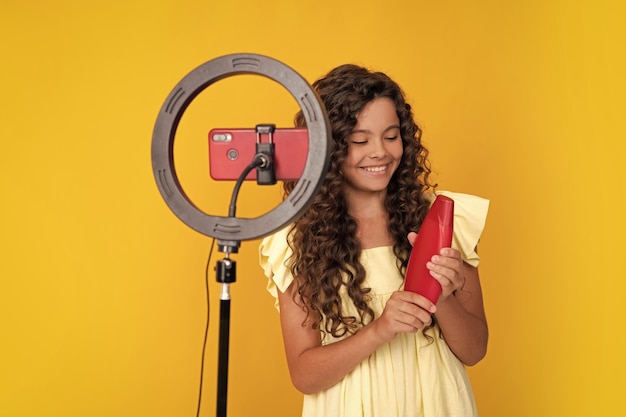 Teen Girl Blogger Influencer halten Haarspülung oder Shampoo-Flasche verwenden Selfie-LED-Lampe