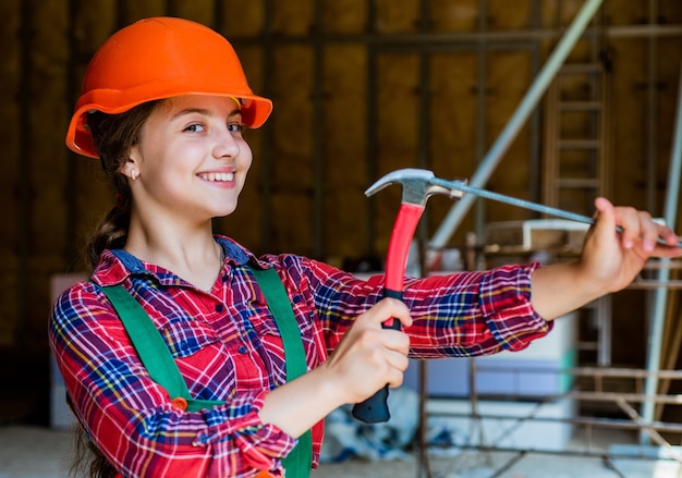 Teen Girl Builder in Schutzhelm verwenden Hammer, Reparatur.