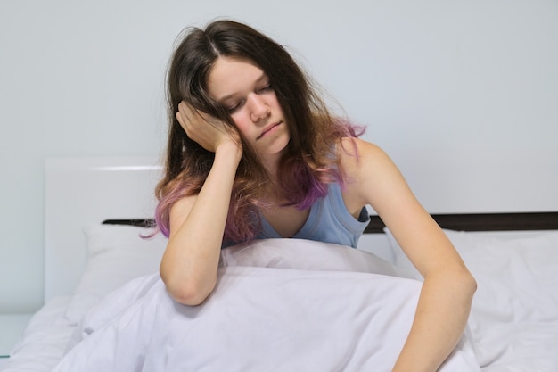 Teen Mädchen, das zu Hause im Bett schläft, morgens schlafend sitzend