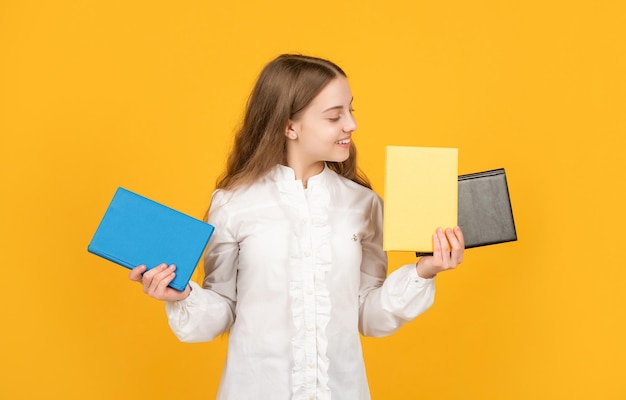 Teen Mädchen machen Hausaufgaben mit Schreibheft. mit Arbeitsbuch lernen. fröhliches Kind, das Buch präsentiert. zurück zur Schule. Kindliche Bildung. Tag des Wissens. Kind halten Notizbuch. Schüler im Gymnasium.