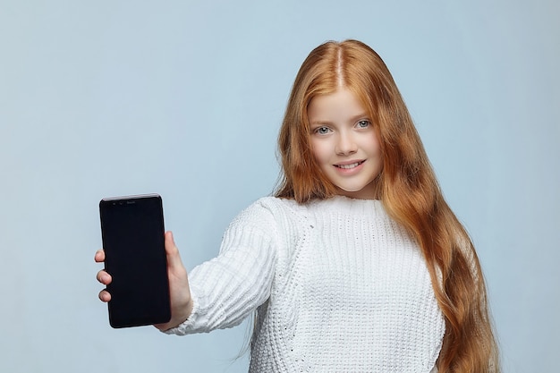 Teen Mädchen mit langen roten Haaren zeigt Smartphone