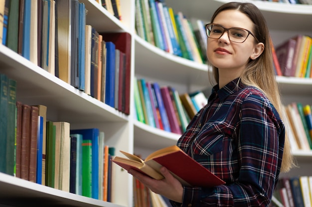 Teen mit einem Buch in den Händen steht in der Bibliothek.