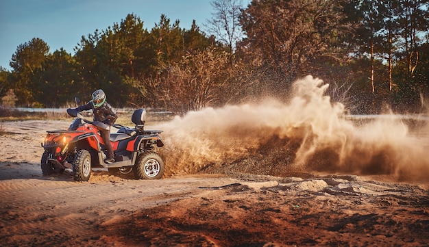 Teen montando un ATV en las dunas de arena haciendo un giro en la arena