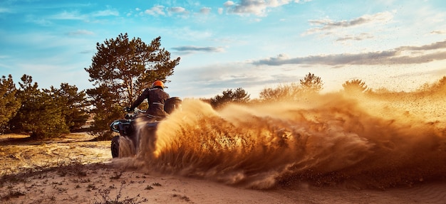 Teen montando un ATV en las dunas de arena haciendo un giro en la arena