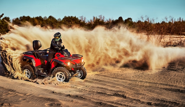 Teen montando un ATV en las dunas de arena haciendo un giro en la arena