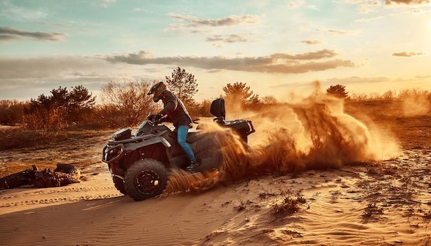 Teen montando un ATV en las dunas de arena haciendo un giro en la arena