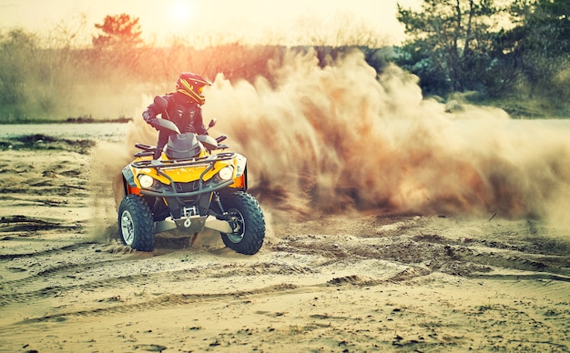 Teen reitet atv in sanddünen und macht eine kurve im sand