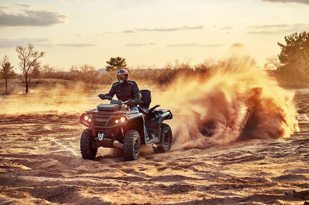 Teen reitet ATV in Sanddünen und macht eine Kurve im Sand