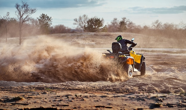 Teen reitet ATV in Sanddünen und macht eine Kurve im Sand