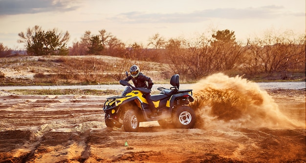 Foto teen reitet atv in sanddünen und macht eine kurve im sand