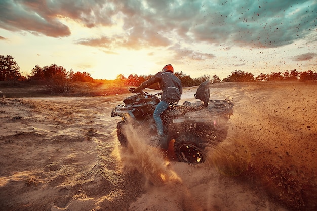 Teen reitet ATV in Sanddünen und macht eine Kurve im Sand