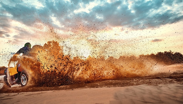 Foto teen reitet atv in sanddünen und macht eine kurve im sand