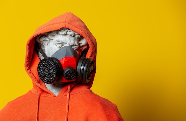 Teen Skulptur in orange Hoodie und Gesichtsmaske auf gelbem Hintergrund