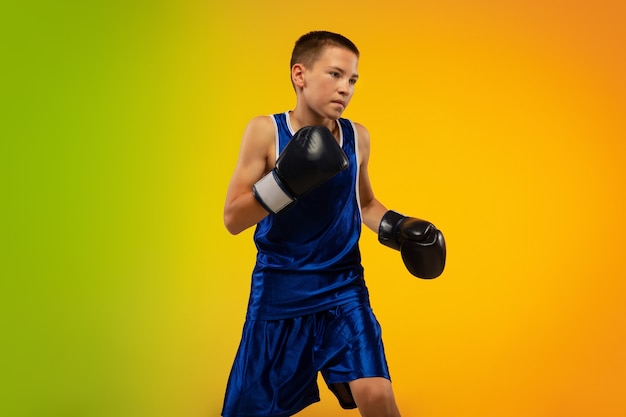 Teenager-Boxer gegen Gradienten-Neon-Studio-Hintergrund in Bewegung des Tretens, Boxen