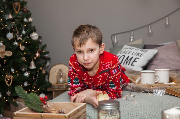 Teenager, der auf einem Bett in einem weihnachtlich dekorierten Schlafzimmer liegt, Neujahrskonzept