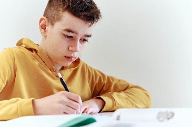 Teenager, der Hausaufgaben zu Hause schreibt. Bildungskonzept