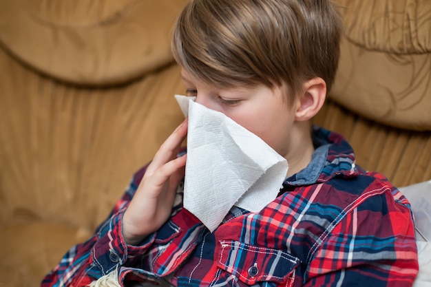 Teenager, der ihre laufende Nase in Papiertaschentaschentuch zu Hause putzt. Chronisch laufende Nase beim Kind. Symptom des Covid-19-Atemwegsvirus.