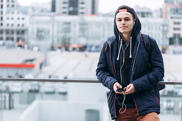 Teenager, der Musik hört und Telefon im städtischen Rahmen benutzt