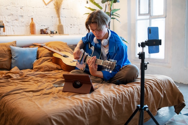 Foto teenager, der musik mit seiner gitarre in seinem heimstudio aufnimmt