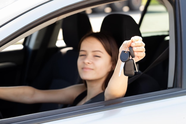 Teenager-Fahrer lernt Autofahren und bekommt einen Führerschein. Konzept: Teenager-Mädchen mit Schlüsseln am Steuer eines Autos