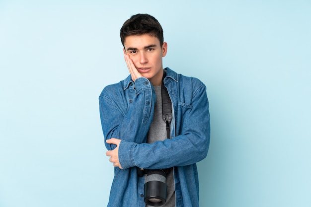 Teenager Fotograf Mann isoliert auf blaue Wand unglücklich und frustriert