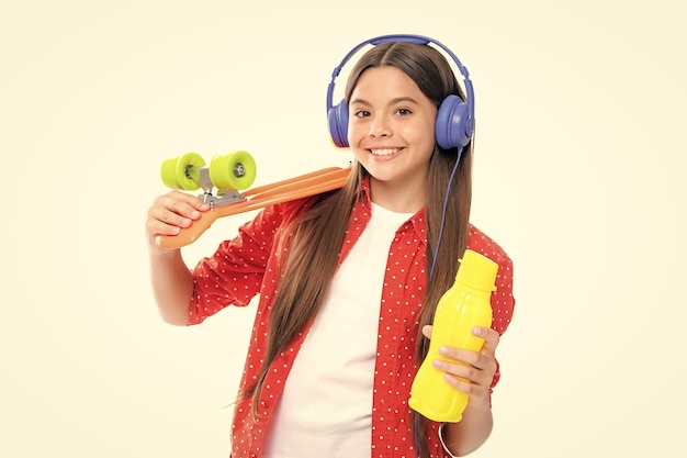 Teenager Jugend Casual Kultur Teen Mädchen mit Skateboard Wasserflasche und Kopfhörer über isolierte weißen Hintergrund Teenager in Mode stilvolle Kleidung Porträt von glücklich lächelnden Teenager