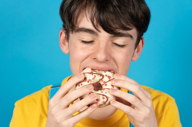 Teenager-Junge genießt süßes Schokoladenbrötchen mit geschlossenen Augen Konzept der Zuckersucht