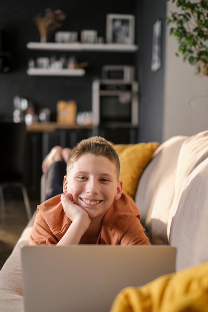 Teenager-Junge lernt oder spielt Spiel auf Laptop-Innenraumhintergrund