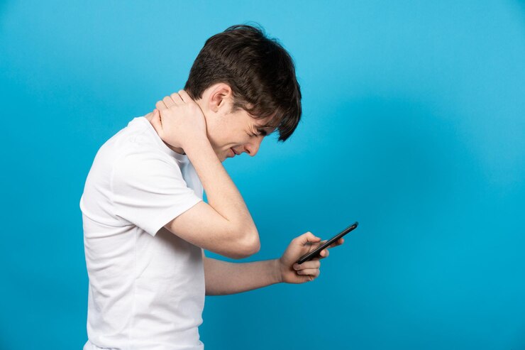 Teenager Junge mit Telefon mit Nackenschmerzen Schlechte Körperhaltung und digitale Sucht nach Pubertätskonzept