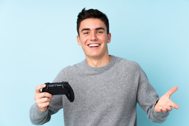 Teenager kaukasischer Mann, der mit einem Videospielcontroller spielt, der auf Blau isoliert wird