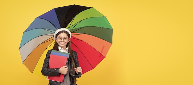 Teenager-Kind der Herbstschule unter buntem Sonnenschirm Kind in Baskenmütze mit Regenbogenregenschirm Herbstsaison Porträt von Schulmädchen Student Studio Banner Header Schulkind Gesicht Copyspace