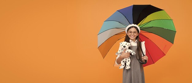 Teenager-Kind des Kindheitsglücks unter buntem Sonnenschirmkind im Baskenmütze mit Regenbogenregenschirm